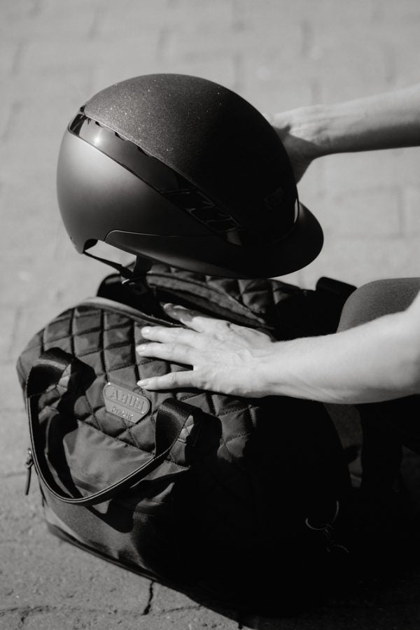 Person placing an equestrian helmet in a quilted Black Horse Riding Helmet Bag