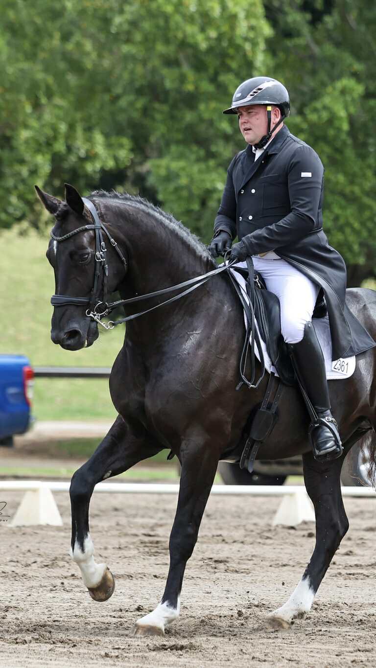 Ryan Fletcher & Dreamtime MI performing dressage in a shiny black equestrian horse riding helmet