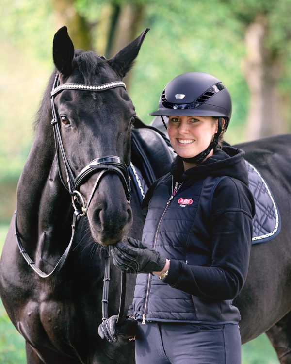 Black equestrian horse riding helmet on a rider with a black horse